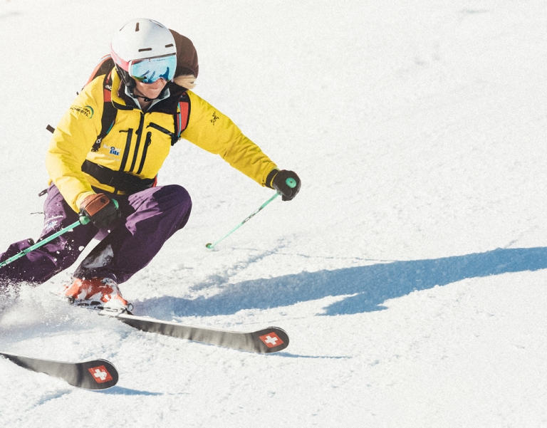 Frau in gelber Skijacke beim Carven