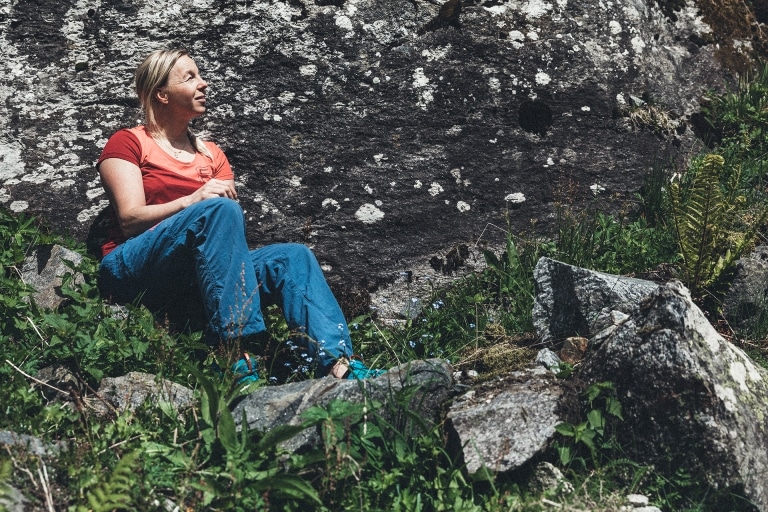 Nina sitzt auf einem Stein vor einer Felswand