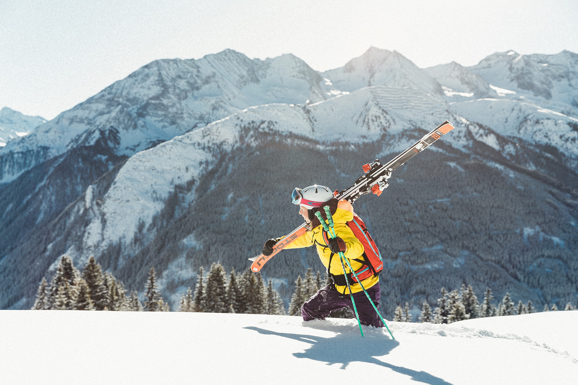 Frau trägt Ski durch den Tiefschnee